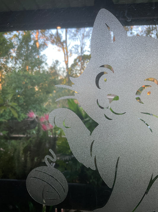 Decorative glass with a cat design and blurred outdoor background